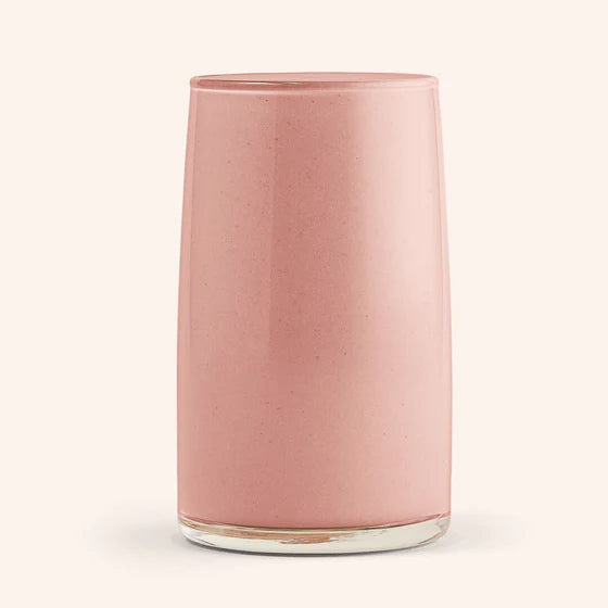 A glass of purple Acai Coconut Ka'Chava shake garnished with berries and a coconut flake.