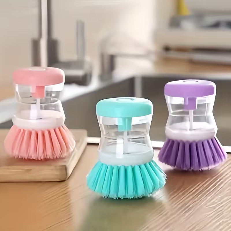 Three colorful dish scrubbers on a wooden surface with a blurred kitchen background.
