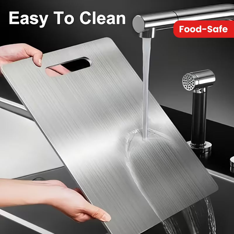 Person washing a metal cutting board under running water with a faucet in the background.