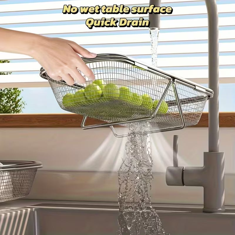 Metal mesh strainer with green apples being rinsed under running water in a kitchen setting.