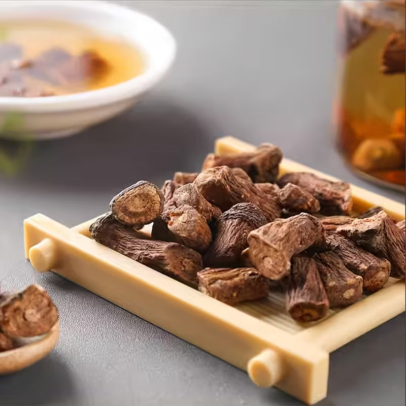 Dried roots on a wooden tray with a blurred background of tea.