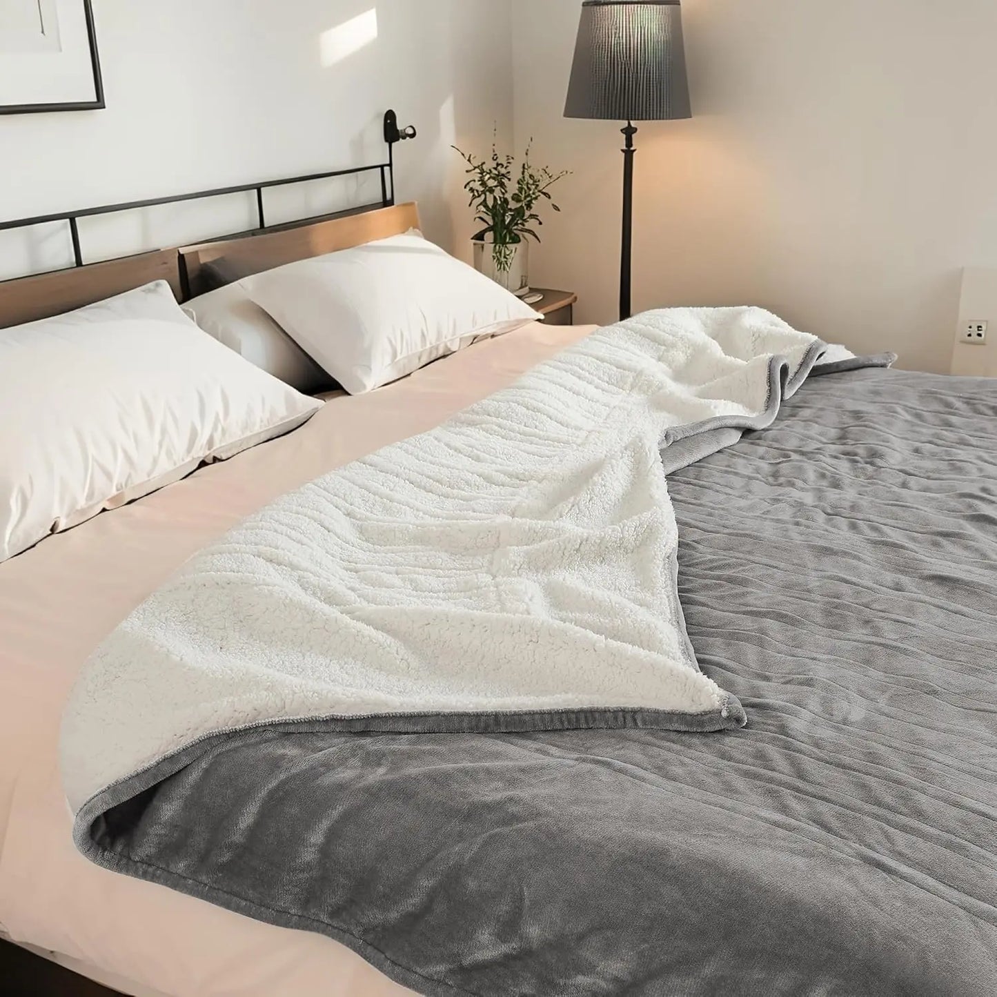 Gray and white blanket draped over a bed in a bedroom setting.