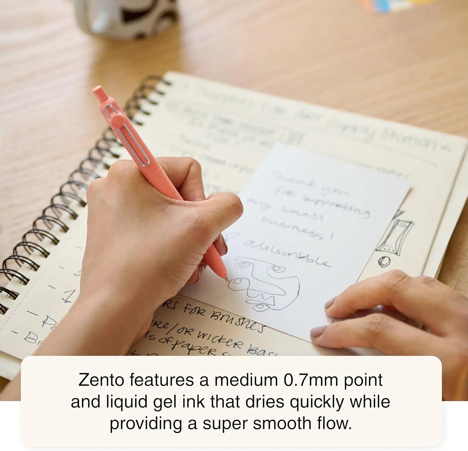 Person writing in a notebook with a pink pen, text about Zento pen features.