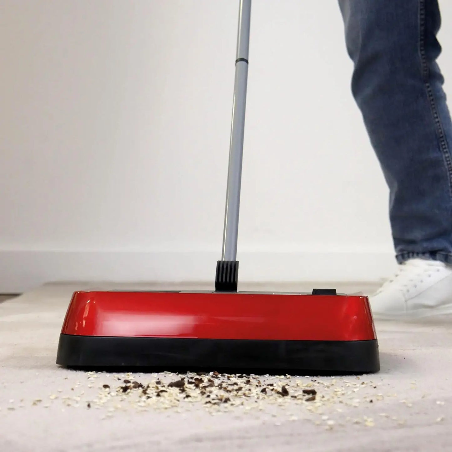 Red and black floor cleaning tool being used on a carpet