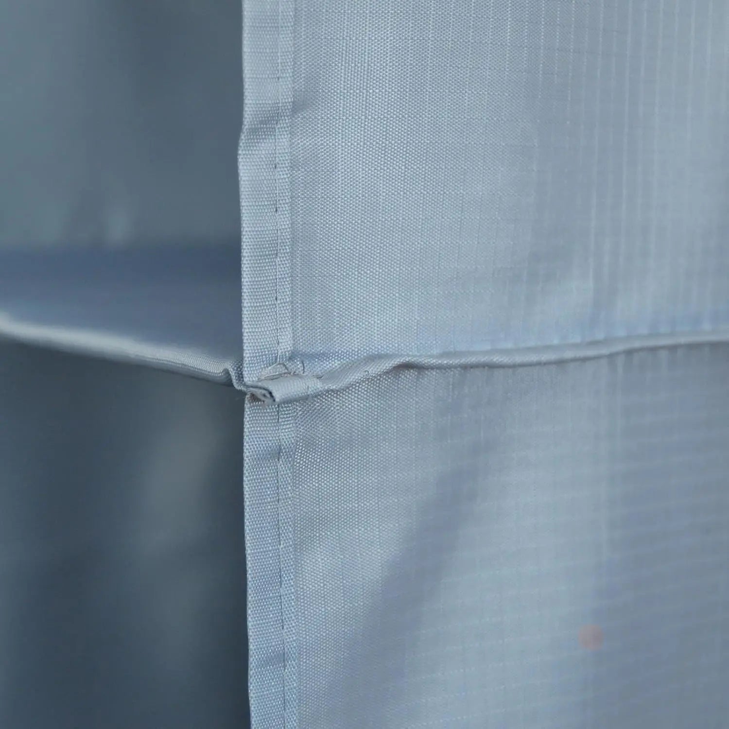 Close-up of a light blue fabric with a subtle pattern on a plain background