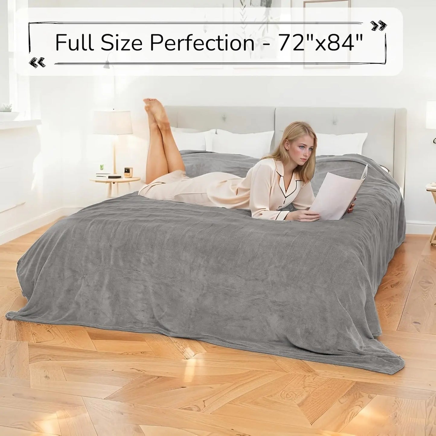 Woman lying on a king-sized bed with a gray comforter, holding a book.