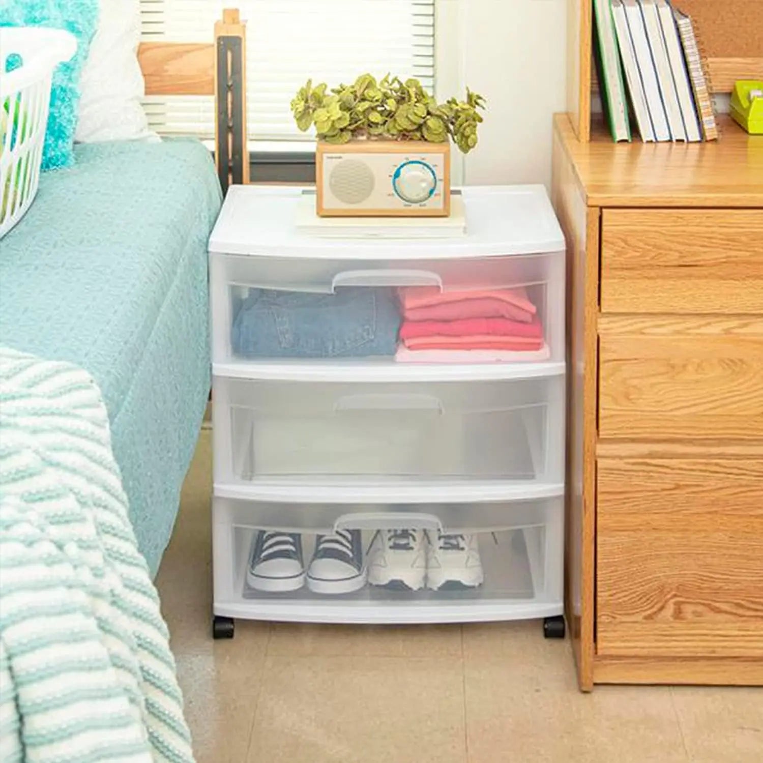 Clear plastic storage drawers with wheels in a bedroom setting.
