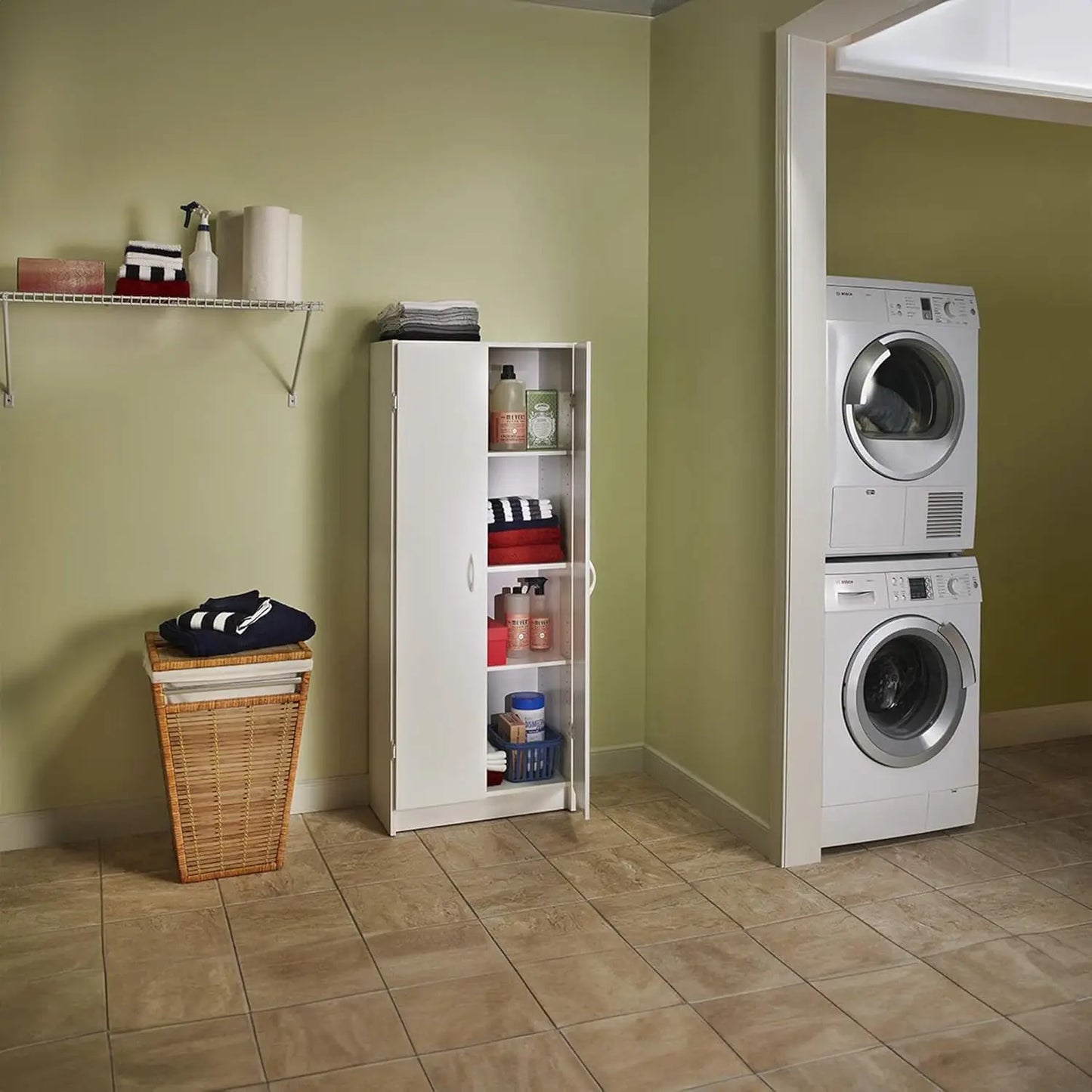 Laundry room with stacked washer and dryer against a green wall, featuring a cabinet and laundry basket.