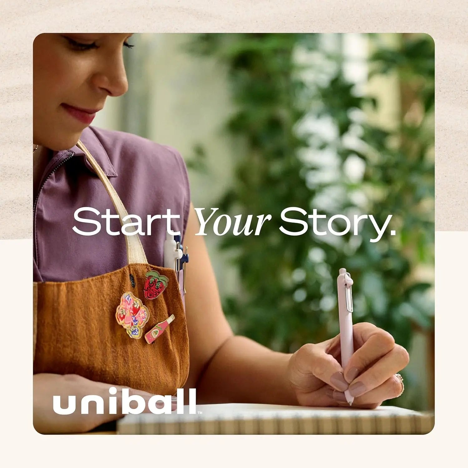 Person holding a pen with 'Start Your Story' text and Uniball logo.