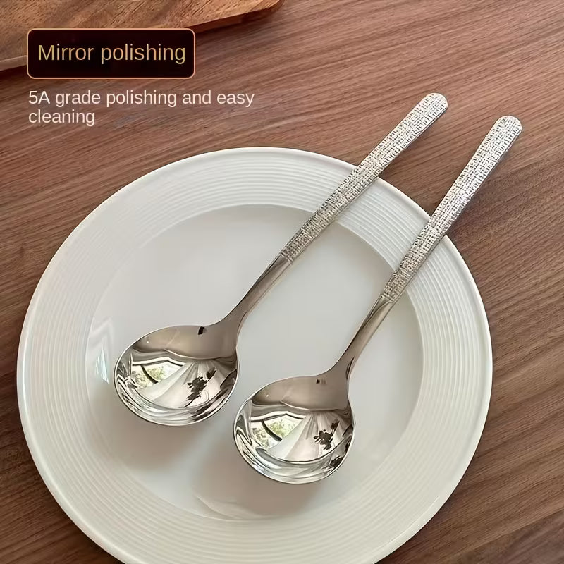 Two silver spoons on a white plate with text about mirror polishing and easy cleaning.