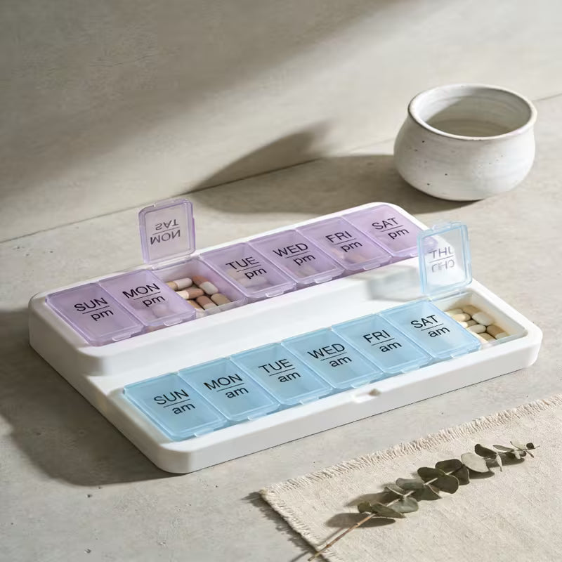 Weekly pill organizer with compartments for different days of the week on a light surface.