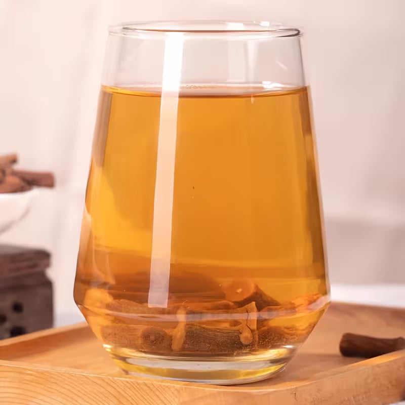 Glass of amber-colored liquid on a wooden surface with a blurred background