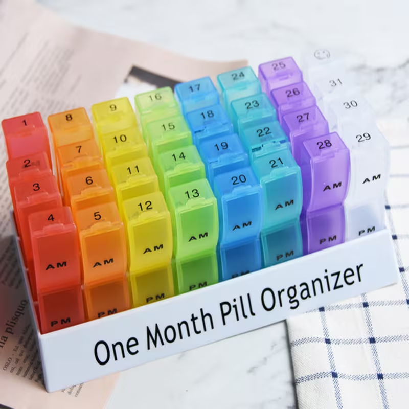 Colorful one-month pill organizer with AM and PM labels on a newspaper background