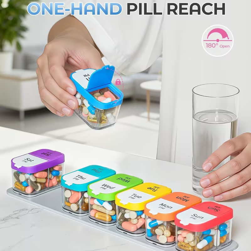 Person using a pill organizer with colorful containers and a glass of water on a table.