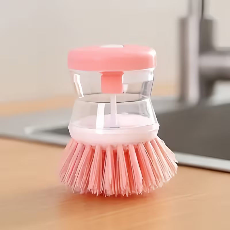 Pink dish scrubber with clear handle on a wooden surface